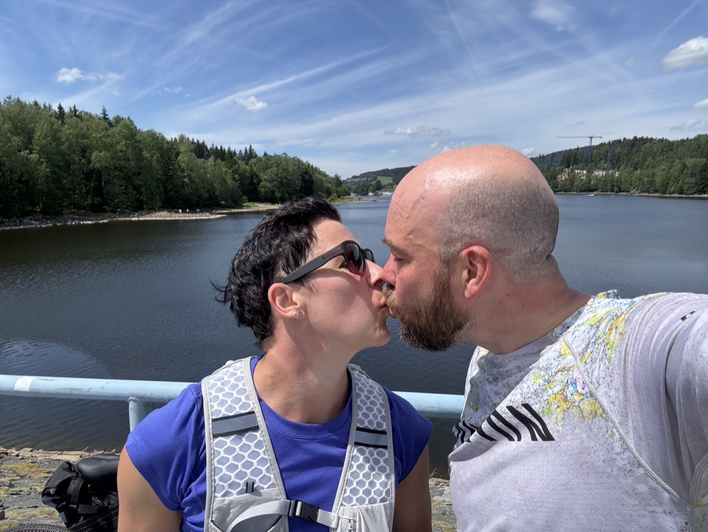 Janett und ihr Partner küssen sich an einem See.